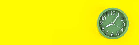 Green alarm clock on bold yellow background, time concept