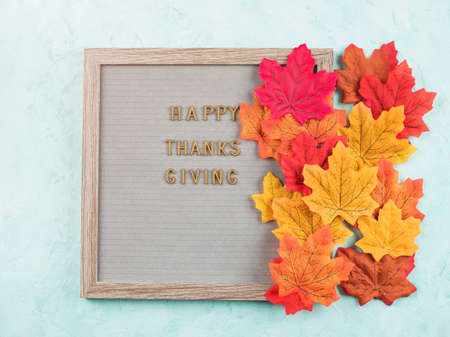 Happy thanksgiving greetings on letter board with autumn red and orange leaves. Seasonal flat lay on...