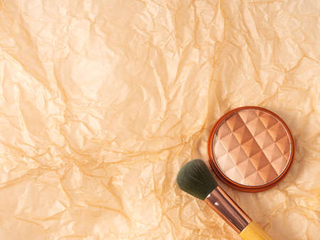 Compact multi color face powder on crumpled beige textured background with application brushの写真素材