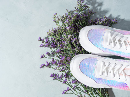 White sneakers with sequins and purple flowers on turquoise backgroundの写真素材