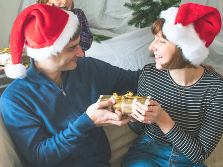 Husband and wife exchanging gifts in santa caps on christmasの写真素材