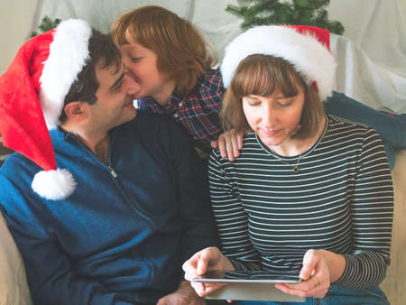Mother, dad and son in santa caps on christmas holidaysの写真素材