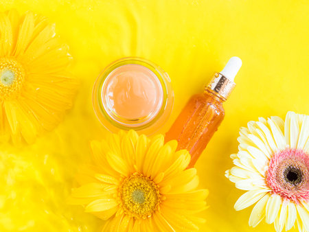 Vitamin C serum and open pink cream on yellow backgroundの写真素材