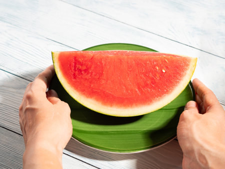 Female hands holding green dish with watermelon in summerの写真素材