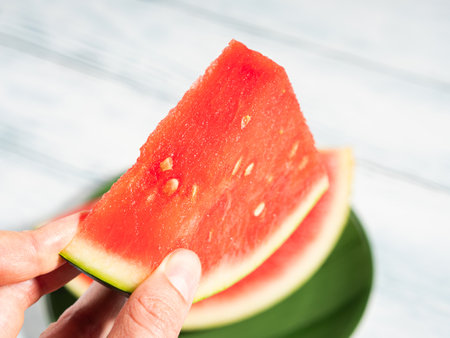 Fingers holding fresh watermelon slice, closeupの写真素材