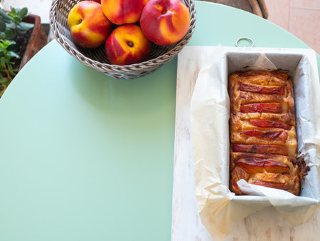 Vegan peach cake in baking mould on green table outdoorsの写真素材