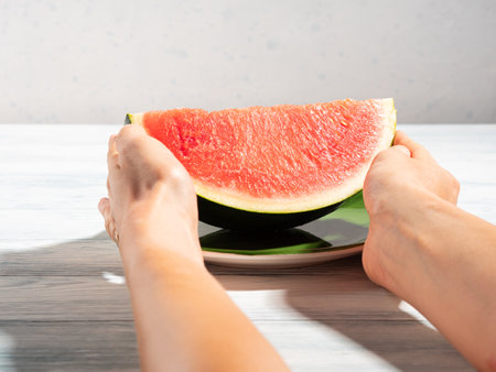 Female hands holding green dish with watermelon in summerの写真素材