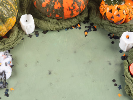 Halloween green frame background flatlay with colorful pumpkins and confettiの写真素材
