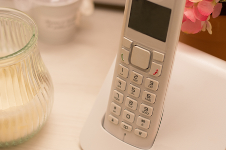 Home phone was next to a candle on a deskの写真素材