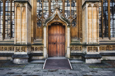 Exterior of the Divinity School in Oxford showing a big wooden door entrance and columns and stained glass windowsのeditorial素材