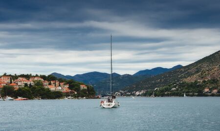 A yacht sailing off into the distance between the hills and mountainsの写真素材