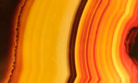 Polished onyx mineral stone with orange, yellow, brown and red stripesの写真素材