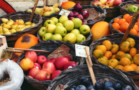 Market vendor cart with varied fruit in wicker basketsの写真素材