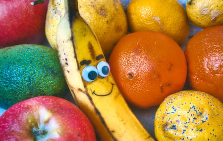 A bowl of fresh fruit with a smiley banana with a cheeky face drawn onの写真素材