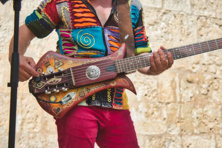 Musician playing live with a colorful weird shaped electric guitarの写真素材