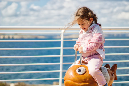 Cute little girl having fun playing on a spring rider / rocking horse in a public parkの写真素材