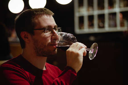 Young man in a restaurant drinking red wine from a glassの写真素材