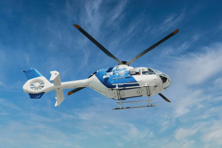 Blue and white air ambulance rescue helicopter flying mid-air against a blue sky backgroundの写真素材