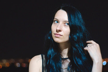 Portrait headshot of an attractive white Caucasian young woman with striking features against a night time dark backgroundの写真素材