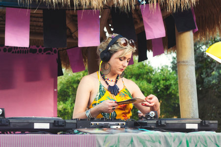 A female DJ using mixing decks with old-fashioned vinyl records outdoorsの写真素材