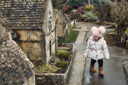 Model village at Bourton on the Water, with a cute white Caucasian girl wearing winter clothes...