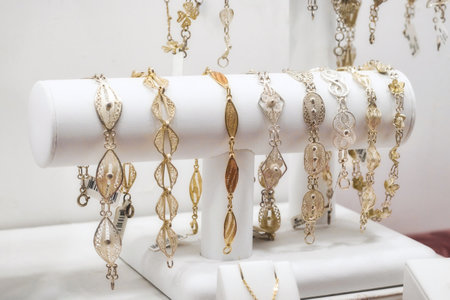 A collection of gold and silver filigree women's bracelets on display in a retail jewellery shopの写真素材
