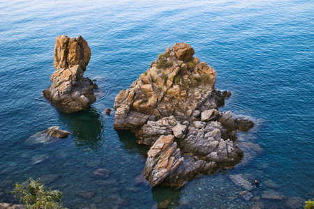 Rocks jutting out of the sea at Spiaggia Caldura beach in Cefalu, Sicily