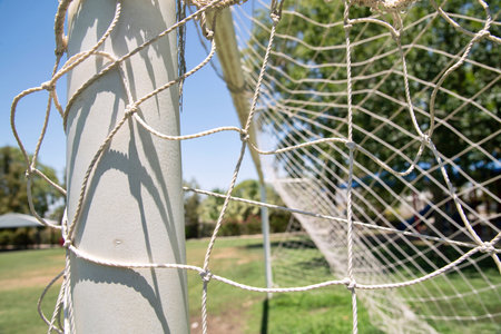 Side-view close-up of a football goal  with netting on a soccer pitch