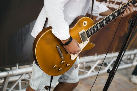 A musician on stage playing of gold colored electric guitar