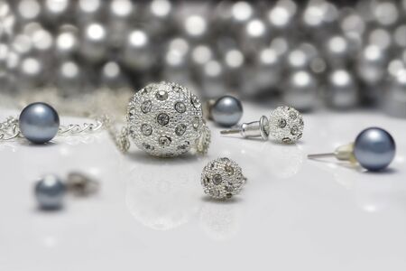 Closeup jewelry sets of studded silver and black pearls earrings and pendants on acrylic board on pearls necklace background.の写真素材