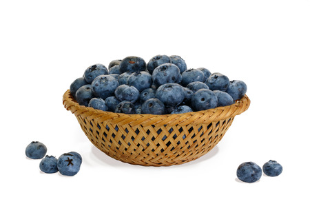 Blueberry in wicker basket and small piles on white background isolatedの写真素材