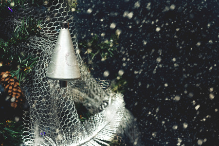 Silver colored bell on Christmas tree by night on background of snowing. Retro styleの写真素材