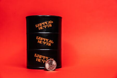 Black oil barrel with a one ruble cent coin on a red backgroundの写真素材