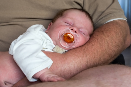 Newborn sleepinh at arms of fatherの写真素材