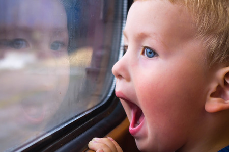 Small boy traveling by train, his face reflected in the glassの写真素材