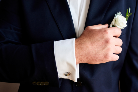 Groom in a suit holding buttonhole. Wedding accessories