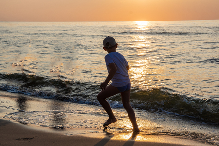A shape of boy at the beach during sunsetの写真素材