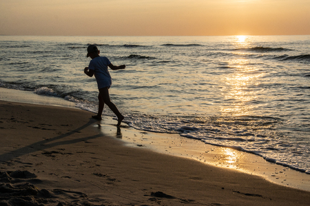 A shape of boy at the beach during sunsetの写真素材
