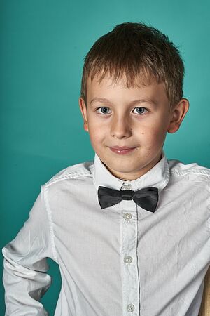 A young caucasian boy weared rhiteshirt and tiebow