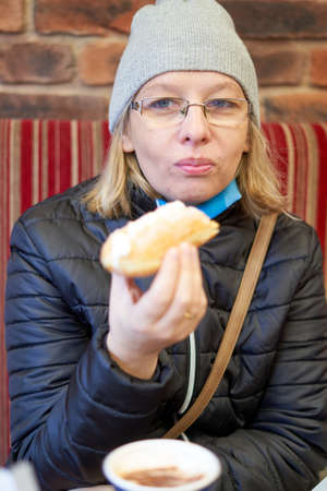 A white woman, eating baguette and drink coffeの写真素材