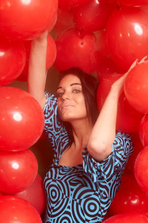 Beautiful brunette girl playing with red baloonsの写真素材