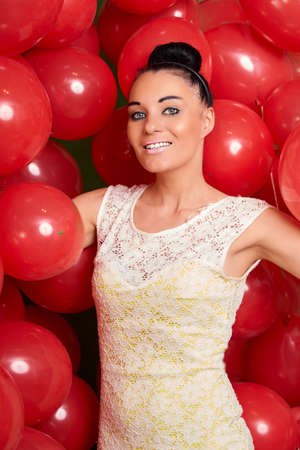 Beautiful brunette girl playing with red baloonsの写真素材
