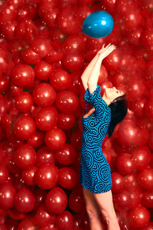 Beautiful brunette girl playing with red baloonsの写真素材