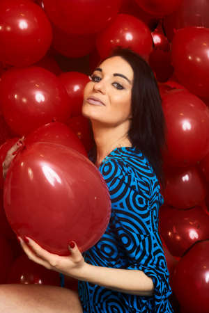 Beautiful brunette girl playing with red baloonsの写真素材