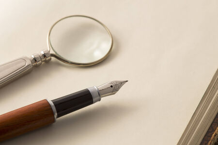 Fountain pen and the magnifying glass on an open notebookの写真素材