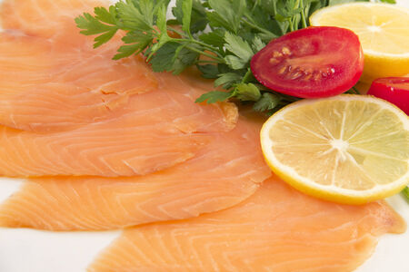 Smoked salmon sliced with lemon, parsley and cherry tomatoの写真素材