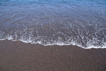 Black sand and the sea water on Santoriniの写真素材