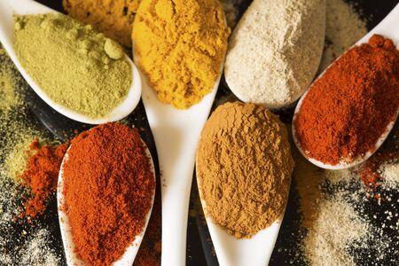Various spices in a white porcelain spoons