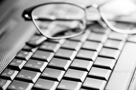 Black laptop keyboard and glasses close up