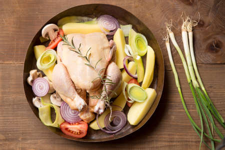 Preparation for roasting chicken with herbs and vegetables in a copper potの写真素材
